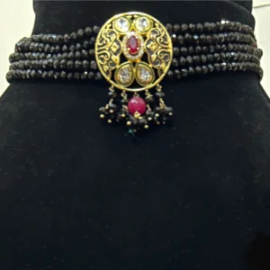 Black Beaded Choker with Metallic Golden Centerpiece displayed on a black colour stand