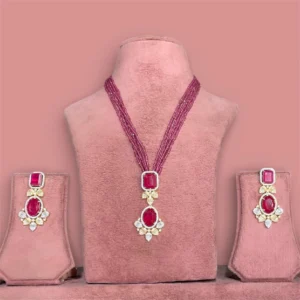 Ruby pink beaded jewellery set with large diamond-style pendant in ruby pink stone and matching earrings on pink display stand