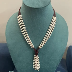 Captivating White Pearl Moti Mala with Maroon Beads displayed on a light green colour stand