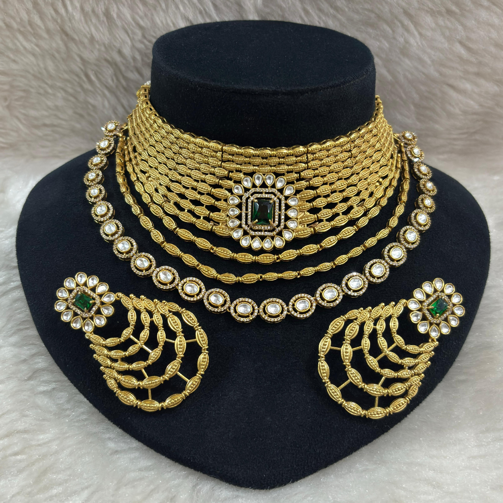 Golden Kundan Bridal Jewellery Set 3 Golden Kundan Bridal Jewellery Set with Emerald green stone displayed on a black colour jewellery stand